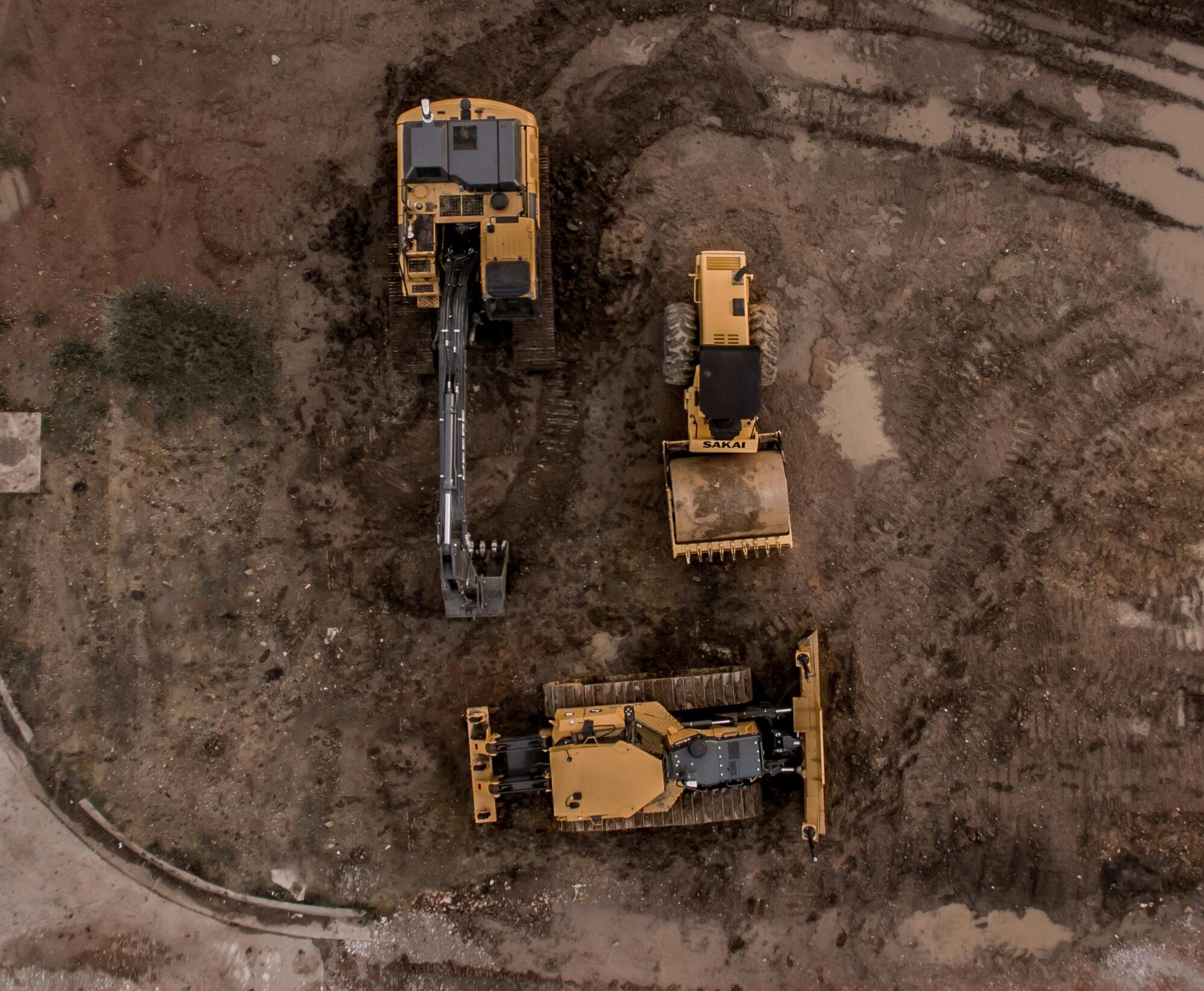 An aerial shot of heavy machinery at a construction site, including excavators and road rollers.