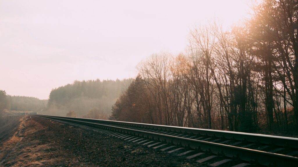 Foggy railway track through a misty autumn forest in Belarus, capturing serene nature and transportation scene.